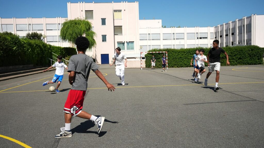 Des collégiens jouent au ballon dans la cour de récréation