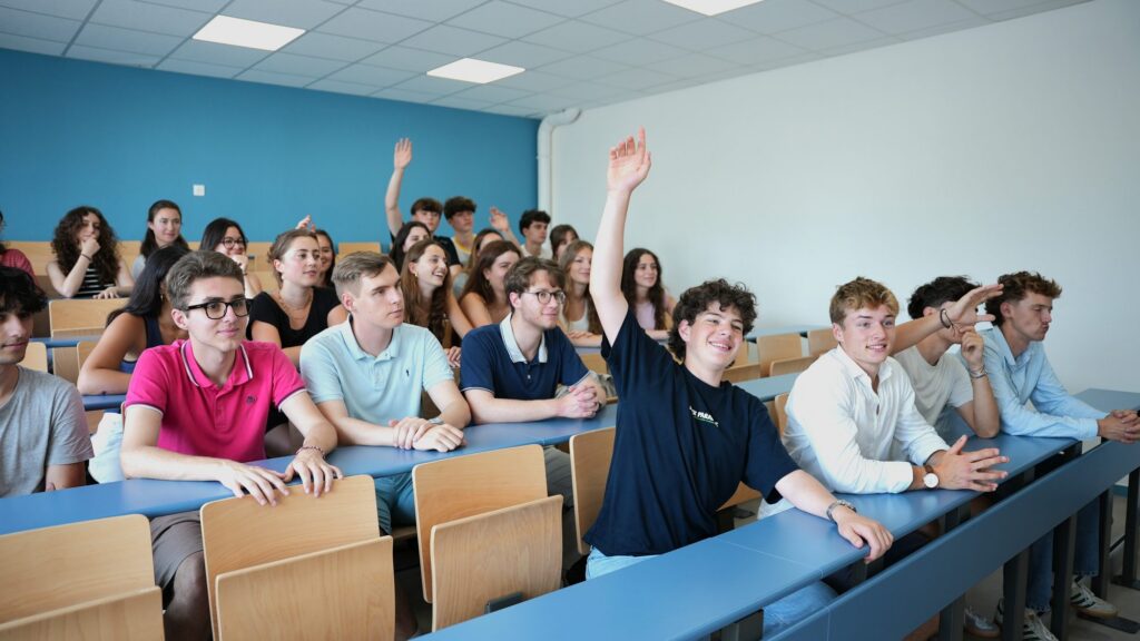 Des collégiens lèvent la main dans l’amphithéâtre