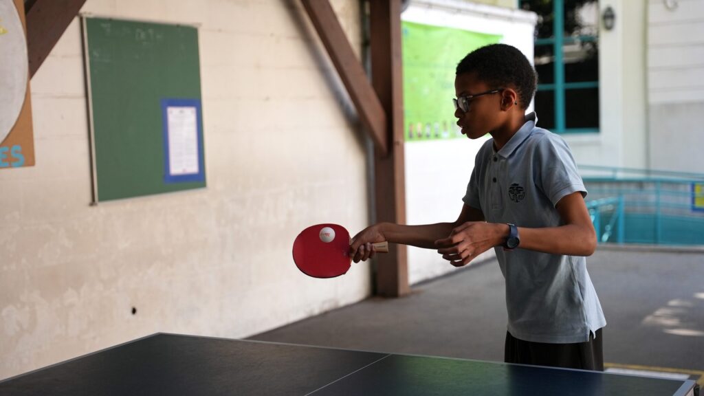 Un écolier joue au tennis de table pendant la récréation
