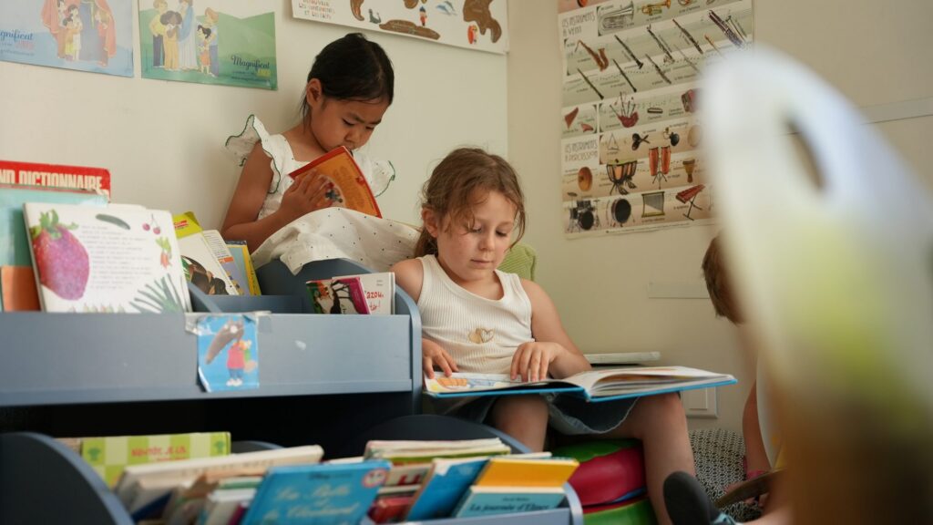 Des enfants de maternelle regardent des livres avec leur enseignante